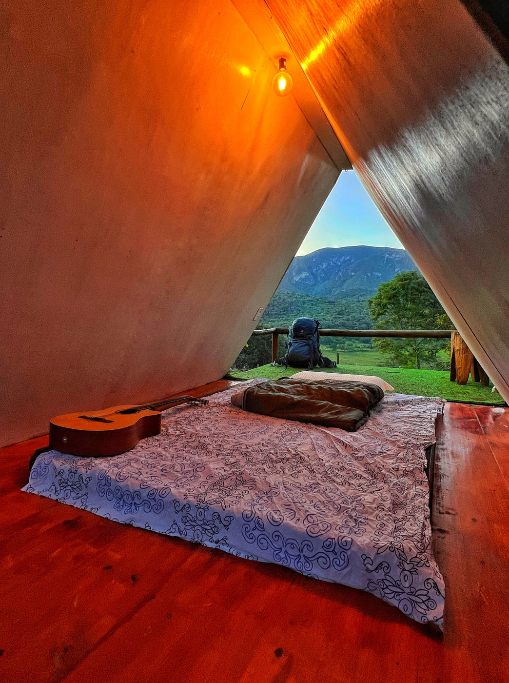 Interior de uma tenda com colchão de casal e vista para a serra